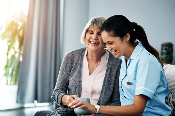 Caregiver laughing with elderly woman during companionship visit